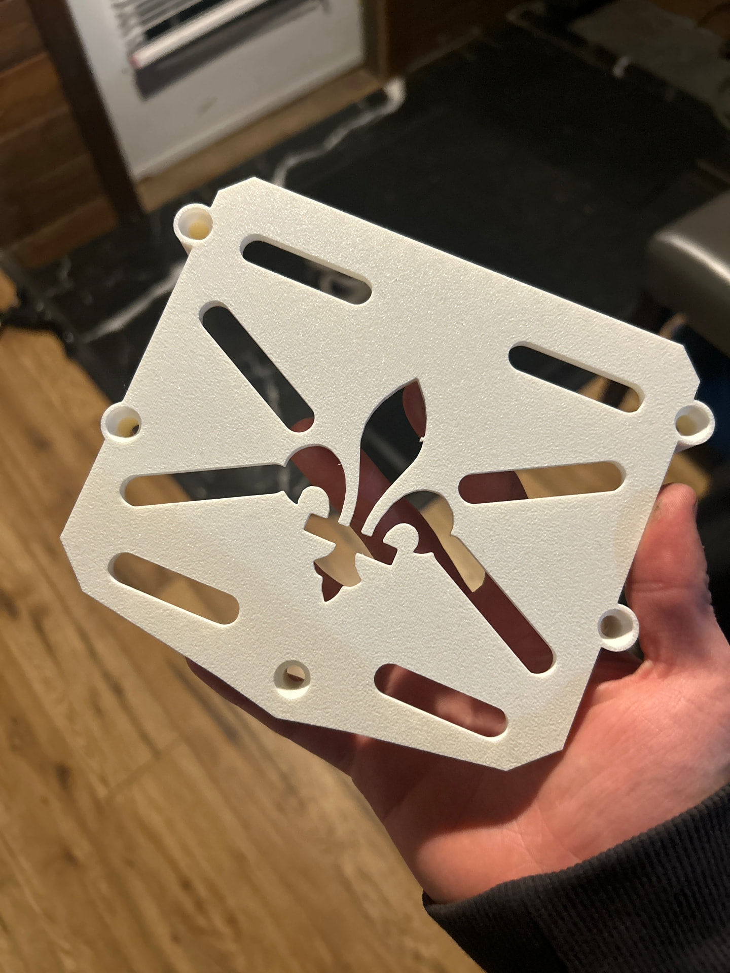 Plaquette Fleur de lys blanche imprimée en 3D tenue dans une main